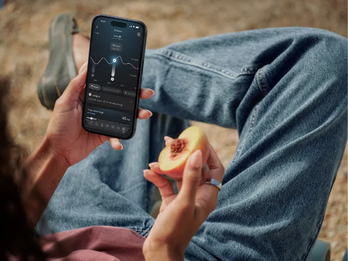 Oura Ring en un dedo junto a la Oura App en el móvil