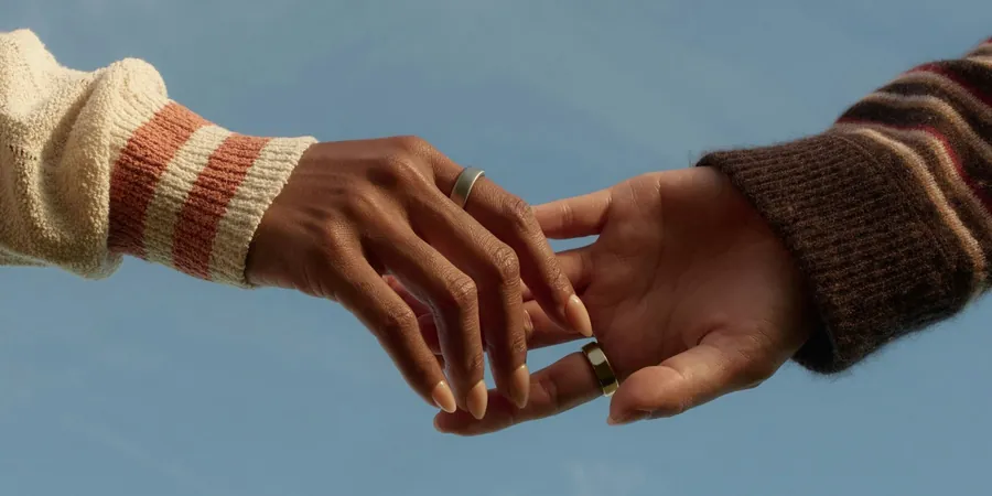 Dos manos con Oura Ring ante un cielo azul